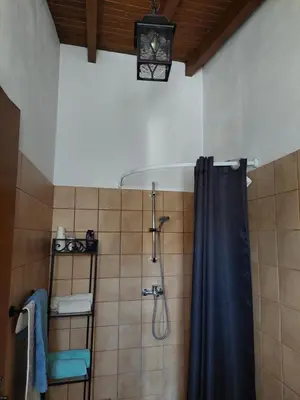a bathroom with a shower with a blue shower curtain at The Little House in Ayios Theodhoros
