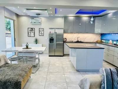 a kitchen with white cabinets and a table in it at Luxury Villa LAPIS LAZULI in Meneou