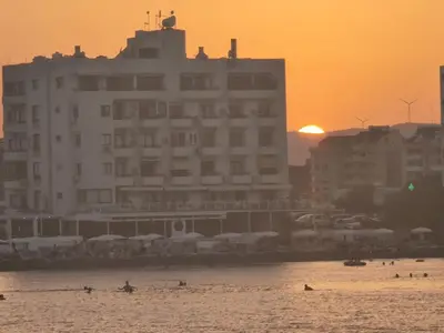 a beach with a large building and people in the water at JUST on the beach Makenzy Studio in Scala