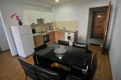 a kitchen with a table and chairs and a white refrigerator at Ithaki Phinikoudes Apartment No. 105 in Larnaka