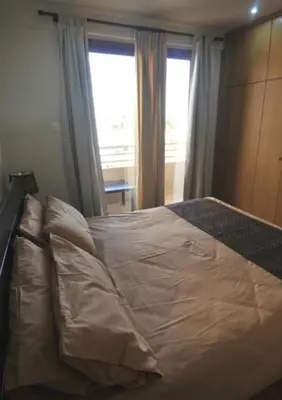 a bedroom with a large white bed with two windows at Ithaki Phinikoudes Apartment No. 105 in Larnaka