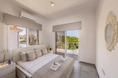 a white bedroom with a bed and a large window at Ayia Napa Bay View Villa 5 in Ayia Napa