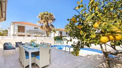 a patio with a table and a lemon tree next to a pool at Sonja in Paralimni