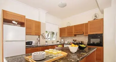 a kitchen with wooden cabinets and a counter top with glasses at Sonja in Paralimni