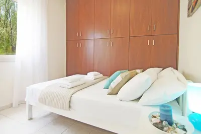 a white bed with a wooden headboard in a room at Sonja in Paralimni