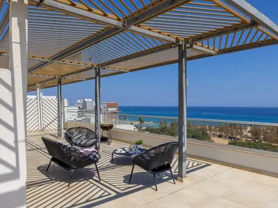 a patio with two chairs and a table and the ocean at Emerald Bay Sea-Front Penthouse in Protaras