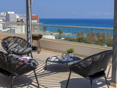 a balcony with two chairs and a table and the ocean at Emerald Bay Sea-Front Penthouse in Protaras