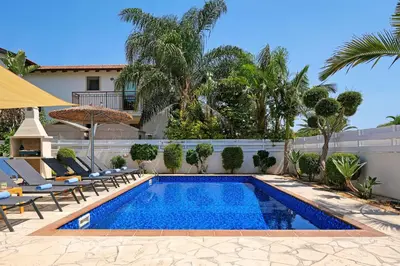 a swimming pool with lounge chairs and a house at Villa Evia - Walking to Med Sea in Ayia Napa