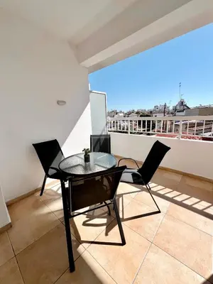 a balcony with a glass table and chairs on a roof at Georgiou 202 in Larnaka