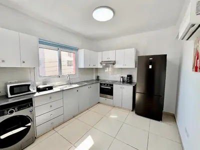 a kitchen with white cabinets and a black refrigerator at Georgiou 202 in Larnaka