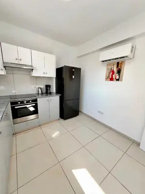 a kitchen with white cabinets and a black refrigerator at Georgiou 202 in Larnaka