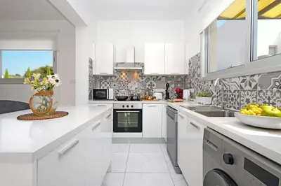 a white kitchen with a vase of flowers on the counter at Villa Rosaleen - Ayia Napa Resort Center in Ayia Napa