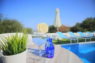 a glass of water and a bottle and a drink at Akefalou Bay Villa in Protaras