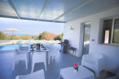a room with white tables and chairs and a pool at Akefalou Bay Villa in Protaras