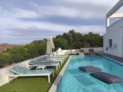 a swimming pool with lounge chairs and umbrellas at Akefalou Bay Villa in Protaras
