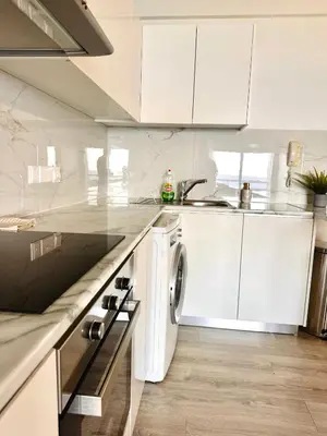 a white kitchen with a sink and a dishwasher at Sea view 3 bedrooms apartment in Limassol