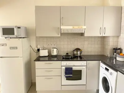 a kitchen with white cabinets and a stove top oven at Star Apt in front Nissi whit Sea View in Ayia Napa