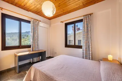 a bedroom with a bed and two windows at JP Pool House in Trimiklini