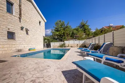 a swimming pool with lounge chairs next to a building at JP Pool House in Trimiklini