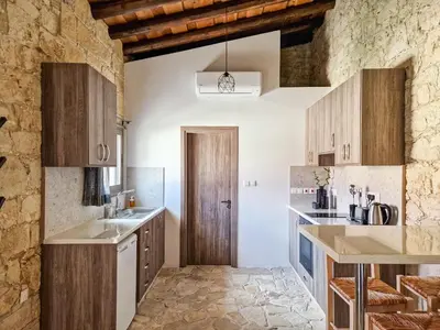 a kitchen with white counters and wooden cabinets at Andre Marie Stonewood Retreat in Limassol