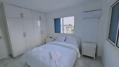 a white bedroom with a bed and a window at STAY Chrisoula Beach Garden in Voroklini