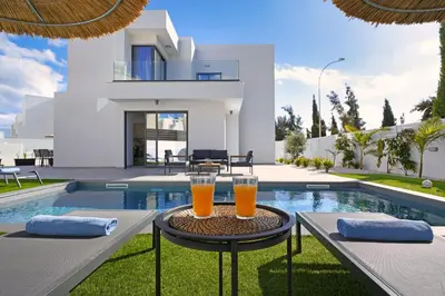 two glasses of orange juice sitting on a table next to a swimming pool at Villa Vitalia - 3 En-suite Beds with Private Pool in Paralimni
