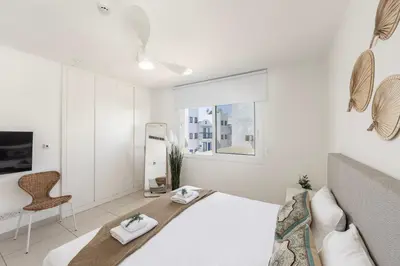 a white bedroom with a bed and a chair at Protaras Sirina Seafront Paradise in Protaras
