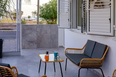 a patio with a chair and a table at FatCow Beach Apartment in Larnaka