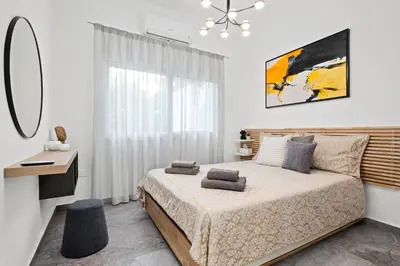 a bedroom with a bed and a desk and a window at FatCow Beach Apartment in Larnaka