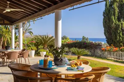 a patio with tables and chairs and the ocean at Ayia Napa Sycamore SeaView in Ayia Napa