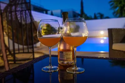 two wine glasses sitting on a table next to a bottle at Hubstay - Blue Harmony Villa in Protaras - 5 min Walk to the Beach in Paralimni