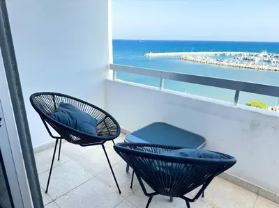 a balcony with two chairs and a view of the ocean at Sea View 1BR With Pool Access in Larnaka
