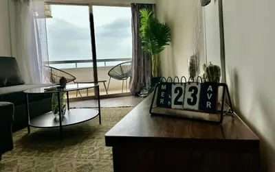 a living room with a couch and a table and a window at Sea View 1BR With Pool Access in Larnaka