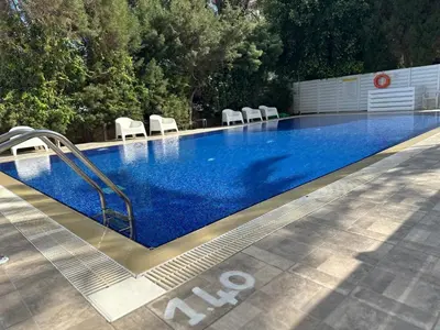 a swimming pool with chairs and a blue pool at Sea View 1BR With Pool Access in Larnaka