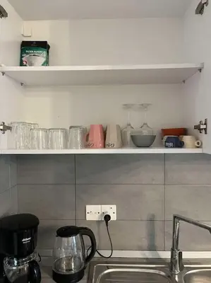 a kitchen with a sink and a shelf with glasses at The Aqua Marine Flat in Iskele