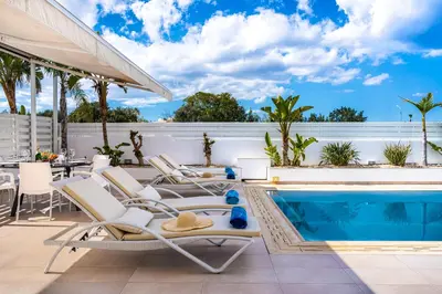 a patio with chairs and a swimming pool at Corali Villa in Pernera Protaras in Paralimni