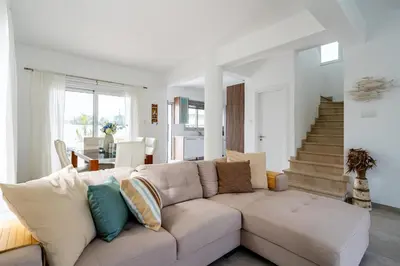 a white living room with a couch and stairs at Corali Villa in Pernera Protaras in Paralimni
