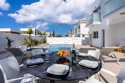 a patio with a table and chairs and a pool at Corali Villa in Pernera Protaras in Paralimni