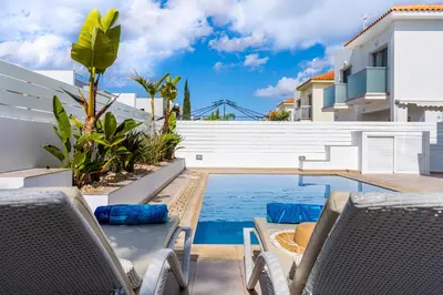 a patio with chairs and a swimming pool at Corali Villa in Pernera Protaras in Paralimni