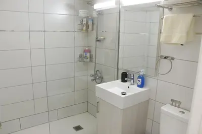 a white bathroom with a sink and a shower at Spacious Apartment, NEAR PINIKOUDES BEACH in Larnaka