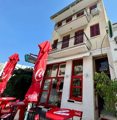 a building with red umbrellas in front of a restaurant at It can't be more central Larnaca in Larnaka