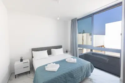 a bedroom with a bed and a large window at Aqua Pearl Villas in Protaras