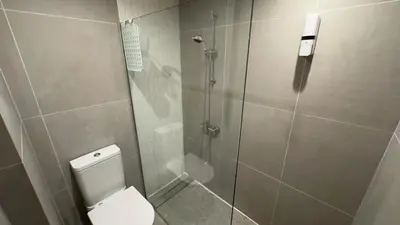 a bathroom with a shower with a toilet and a glass door at Kolonaki Seaview 1BDR Finikoudes in Larnaka