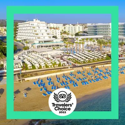 a view of a beach with chairs and buildings at Vrissiana Boutique Beach Hotel in Protaras