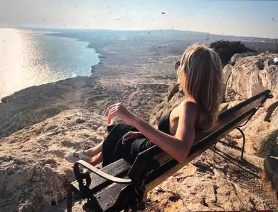 a woman sitting on a bench overlooking the ocean at Vrissiana Boutique Beach Hotel in Protaras