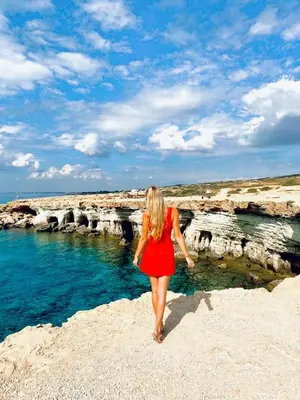 a woman in a red dress walking on the beach at Tsokkos Gardens Hotel in Protaras