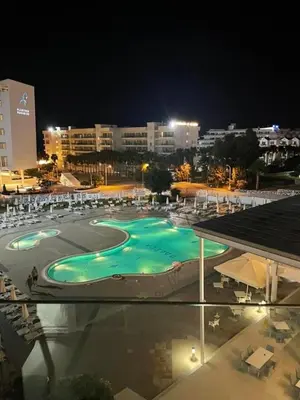 a large swimming pool at night in a city at Odessa Beach Hotel in Protaras