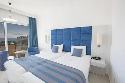 a bedroom with a large bed with a blue headboard at Odessa Beach Hotel in Protaras