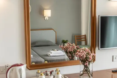 a bathroom mirror with a bed in a room at Antigoni Hotel in Protaras