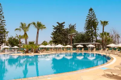 a large swimming pool with chairs and umbrellas at Antigoni Hotel in Protaras